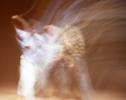 Bewegungsspur mehrerer Tänzer*innen, weiche Lichtschleier in warmem Ton. Wirkt träumerisch und fließend.