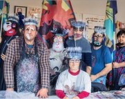 Gruppenbild Menschen mit Masken Kopfbedeckung und Flaggen