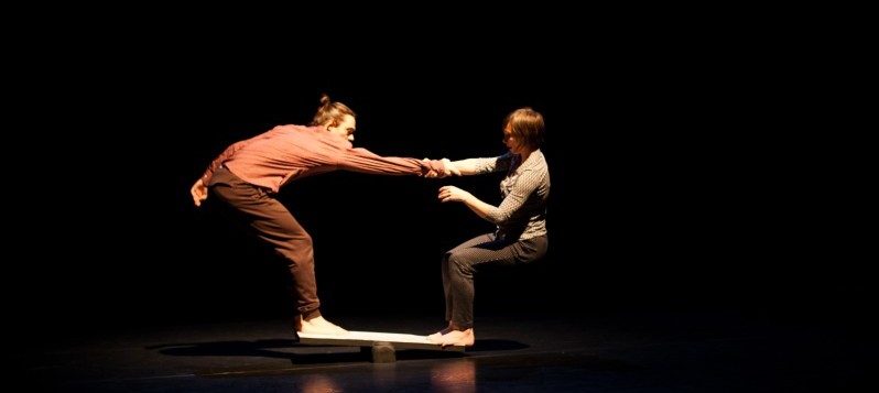 Ein Paar balanciert auf einem Schaukelbrett.