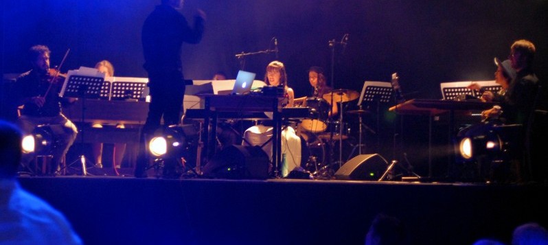 Das Tabula Musica Orchester spielt schummrig warm beleuchtet auf einer erhöhten Bühne.