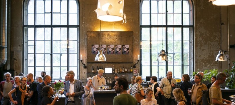 Publikum, Veranstalter und Tänzer:innen kommen in einer schicken Bar zusammen, trinken und unterhalten sich