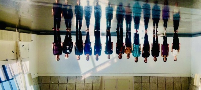 13 Tänzer stehen in einer Reihe. Das Bild ist doppelt gespiegelt.