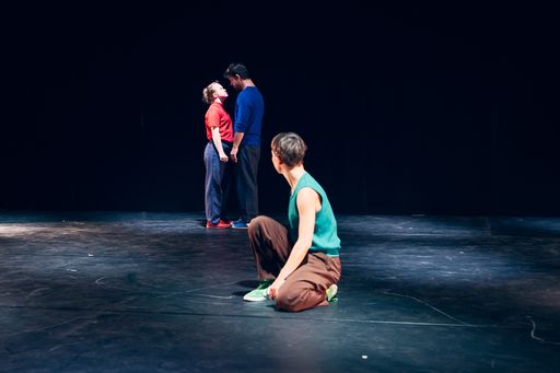 Bühnenaufnahme. Ein Mann trägt einen anderen Mann in gebückter Haltung auf seinem Rücken.