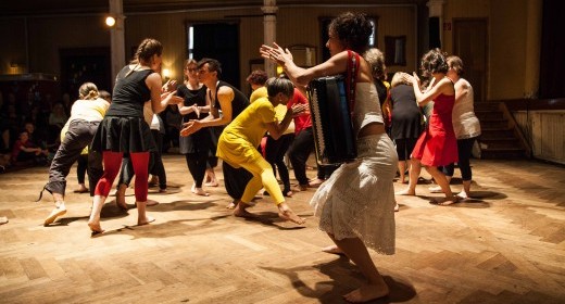 Das Ensemble, hell gekleidet auf einer schwarzen Bühne.