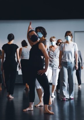 Eine Gruppe von Menschen durchquert mit sich kreuzenden Wegen ein Tanzstudio. Sie rennen, laufen und springen energievoll.