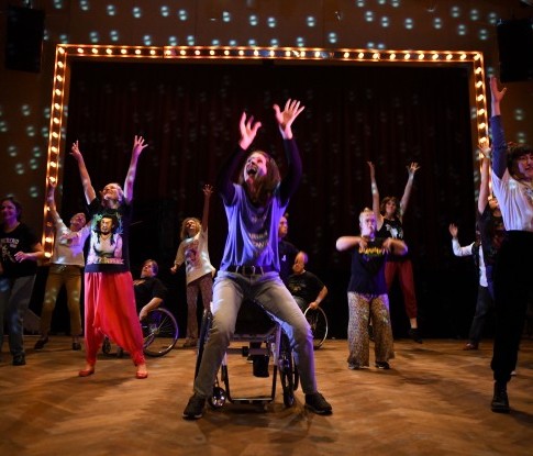 Eine junge Frau mit Mittelscheitel und Zöpfen sitzt hoch konzentriert am Klavier und spielt. Sie trägt ein weisses Kragenhemd, darüber ein schwarzes Gillet mit feinen Glitzertupfen.